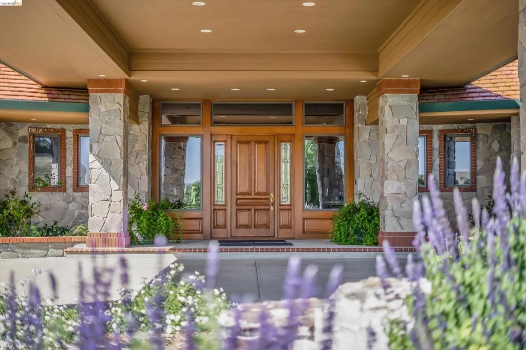 Impressive stone facade entry with a solid wood double door, transom window, and sidelights