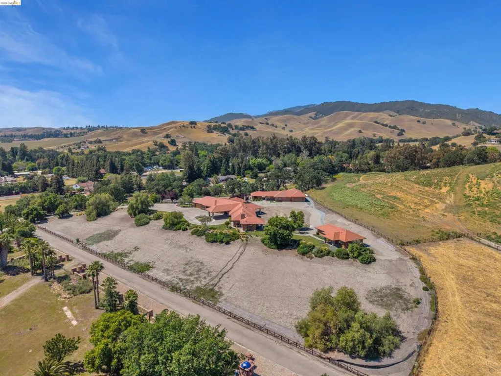 Expansive property featuring a Mediterranean-style residence with a terracotta tile roof, surrounded by mature trees and natural landscaping