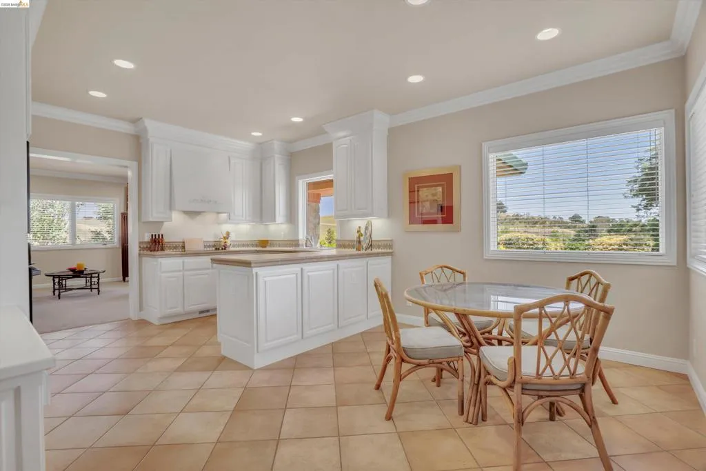 Kitchen featuring tile flooring, white cabinetry, recessed lighting, and a countertop with an integrated sink