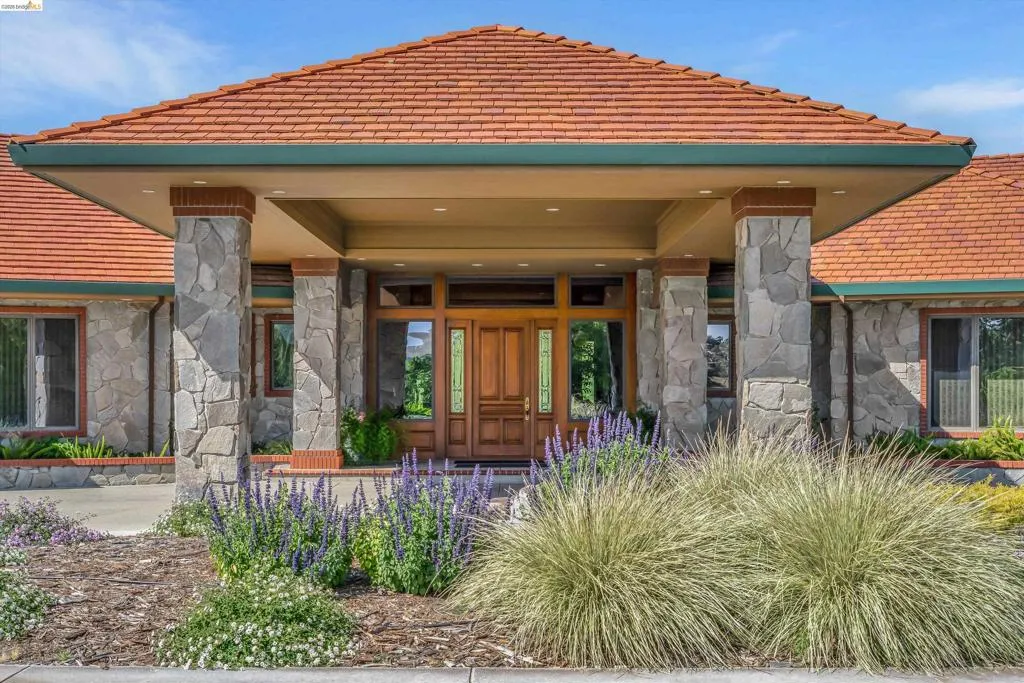 Stone-clad exterior featuring a prominent covered entry with four stone pillars and brick accents