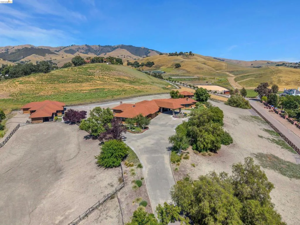 Expansive property featuring multiple structures with terra cotta tile roofs, a paved driveway, and mature landscaping