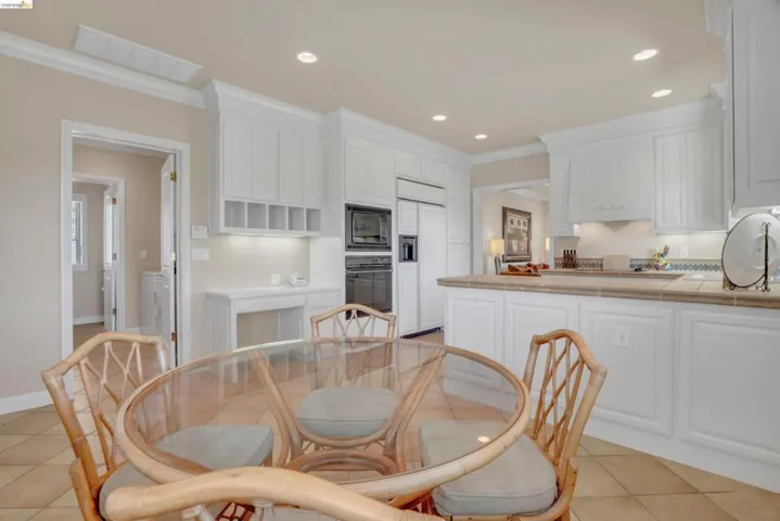 Spacious kitchen featuring white cabinetry, integrated appliances, recessed lighting, and a tiled countertop and backsplash