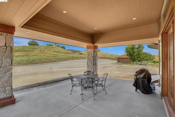 Covered patio featuring stone veneer columns with brick bases, recessed lighting, and a wood-finish ceiling