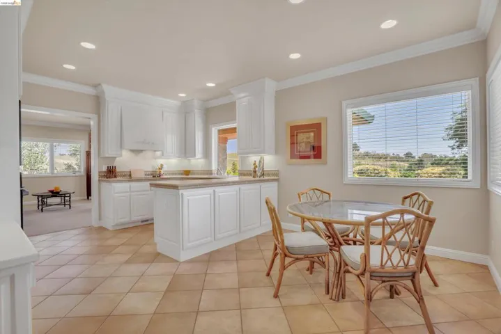 Kitchen featuring tile flooring, white cabinetry, recessed lighting, and a countertop with an integrated sink