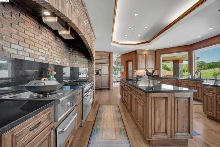 Gourmet kitchen with wood-finish flooring, custom wood cabinetry, and dark countertops