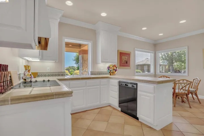 Kitchen featuring white cabinetry, tile countertops, integrated stovetop, recessed lighting, and tile flooring