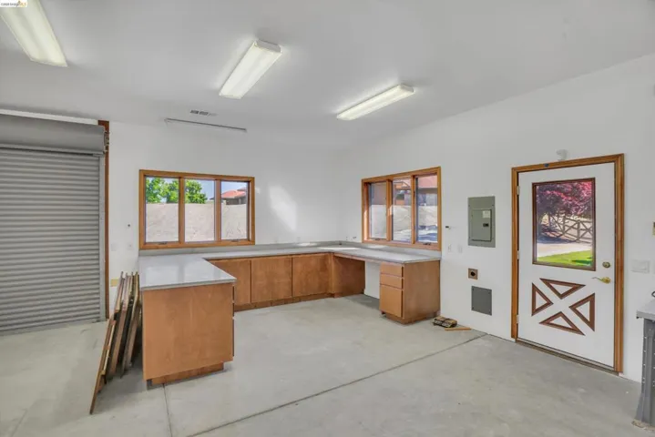 Spacious workspace featuring extensive wood-finish cabinetry with light countertops, multiple windows with wood frames, and fluorescent overhead lighting