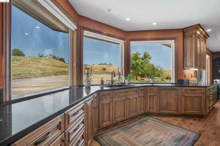Kitchen with rich wood cabinetry, extensive dark countertops, integrated sink, and large windows
