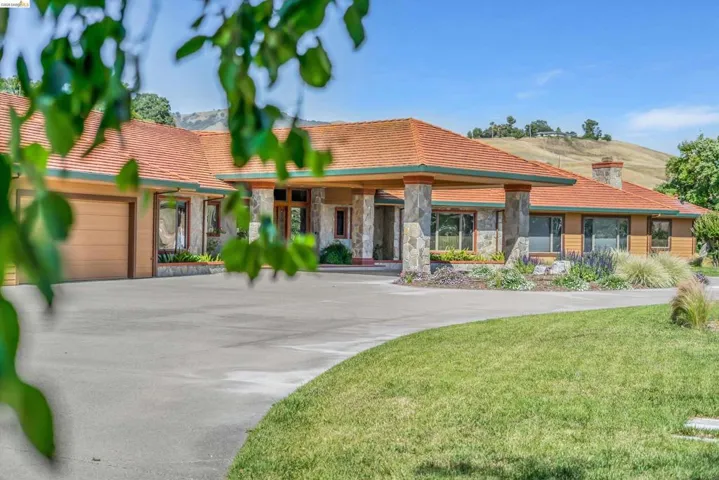 The property features an expansive circular driveway leading to a stone-clad portico entry