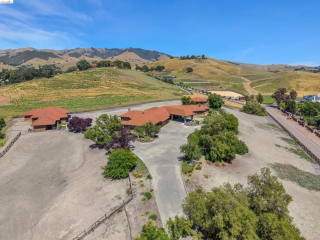 Expansive property featuring multiple structures with terra cotta tile roofs, a paved driveway, and mature landscaping