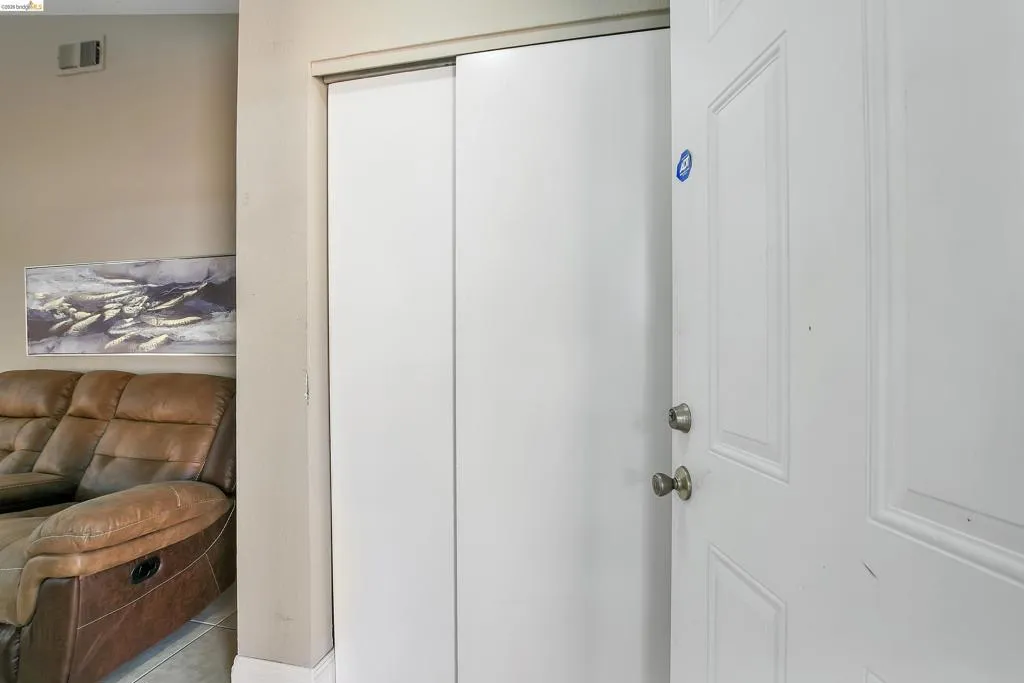 Entryway featuring a paneled white door with brass hardware and a built-in closet with sliding white doors
