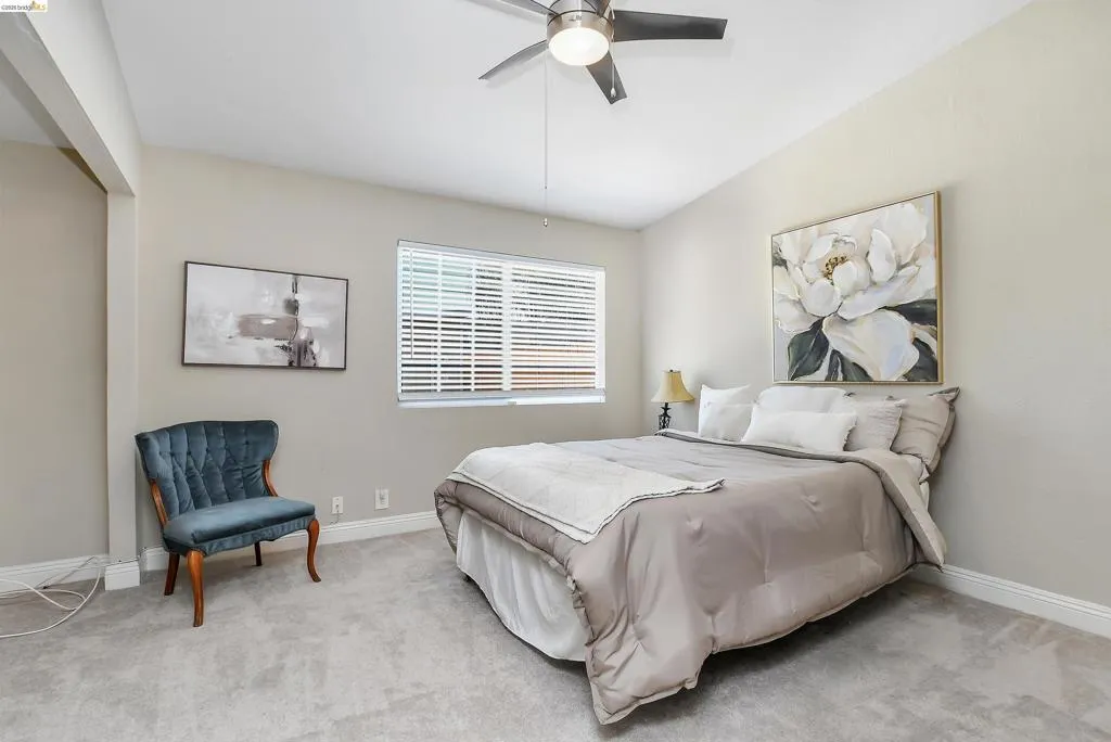 Carpeted bedroom featuring a ceiling fan with integrated lighting, a window with horizontal blinds, and neutral wall tones