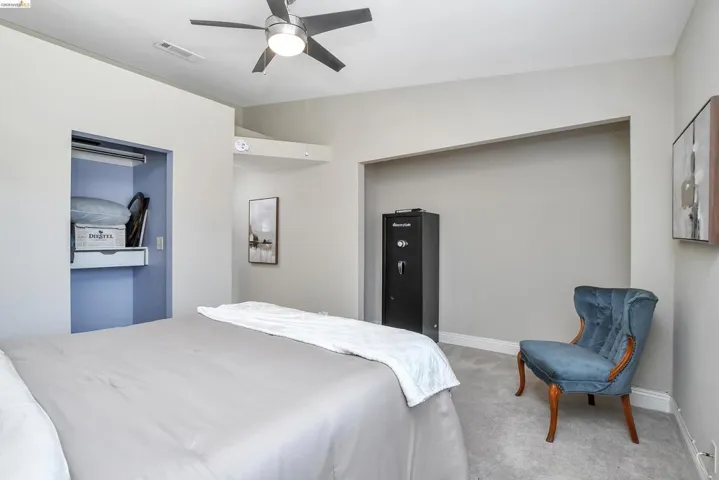 Carpeted room featuring a ceiling fan with integrated lighting, a built-in recessed niche, and an open closet with shelving and a hanging rod