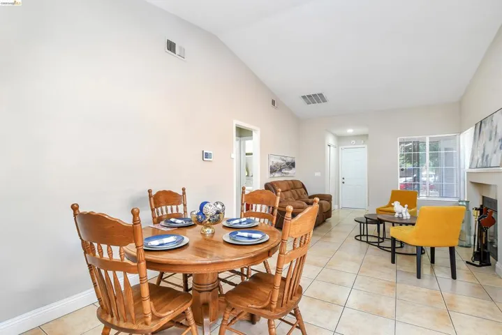 Open-concept living space featuring vaulted ceilings, neutral-toned walls, and tile flooring