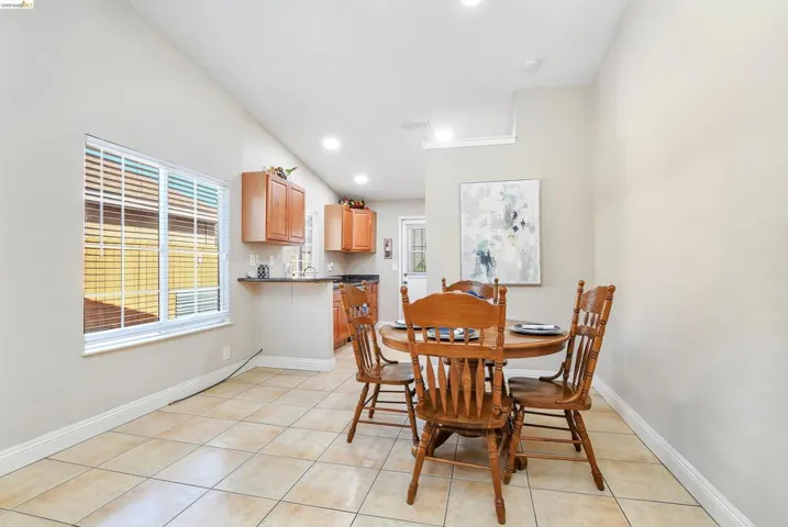 Dining area featuring light-toned tile flooring, a large window with blinds, and recessed lighting