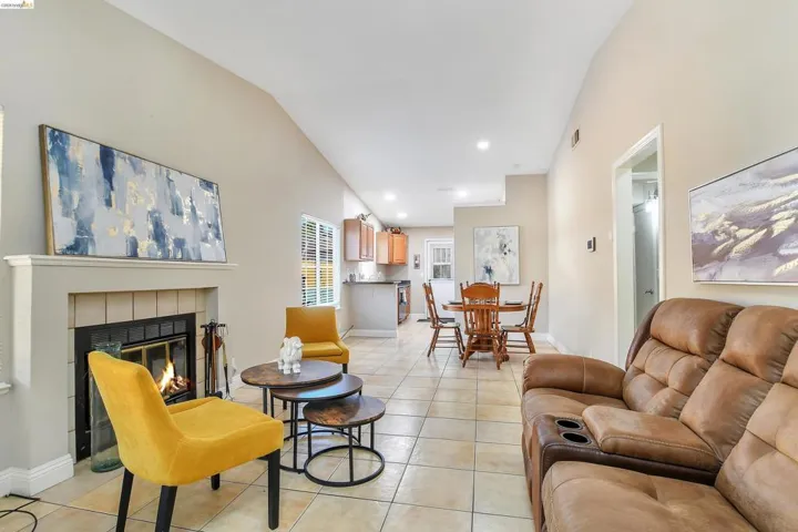 Living area featuring a fireplace with a mantel, tile flooring, recessed lighting, and vaulted ceilings