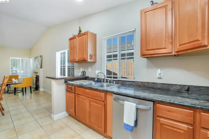 Kitchen featuring wood cabinetry, dark stone countertops, and a double basin stainless steel sink