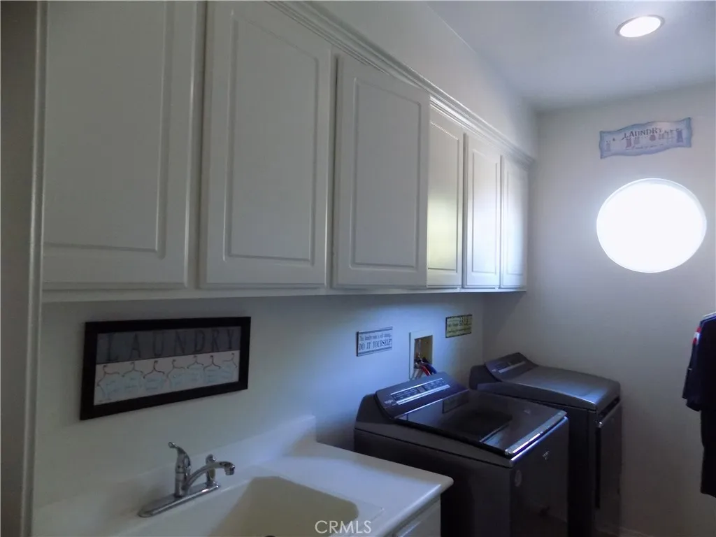Upstairs laundry room with sink and several upper cabinets
