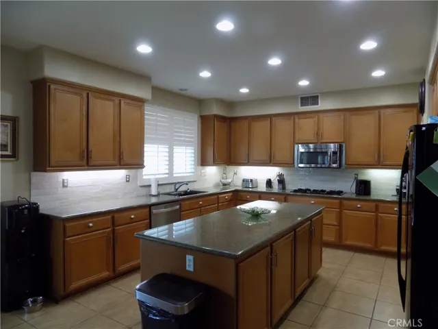 Tiled kitchen with huge island with many cabinets. Notice the subway tile and undermounted lighting