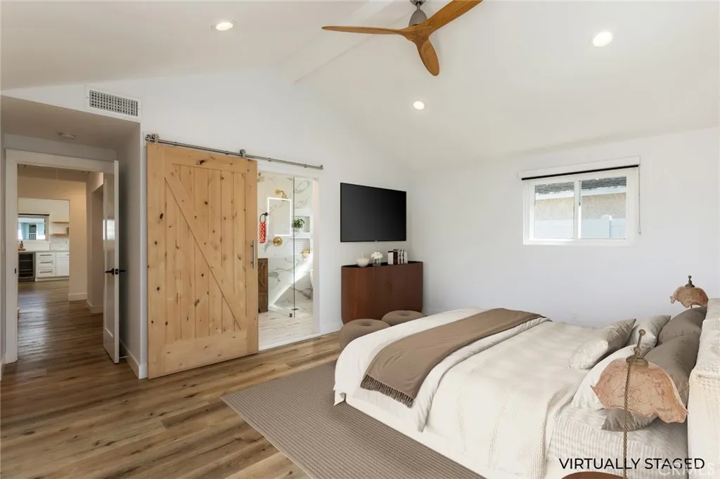virtually staged primary bedroom with barn door to private bathroom