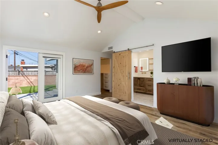 virtually staged primary bedroom featuring a walk in closet and French doors to patio