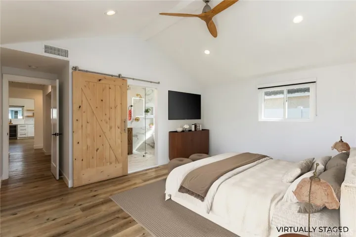 virtually staged primary bedroom with barn door to private bathroom