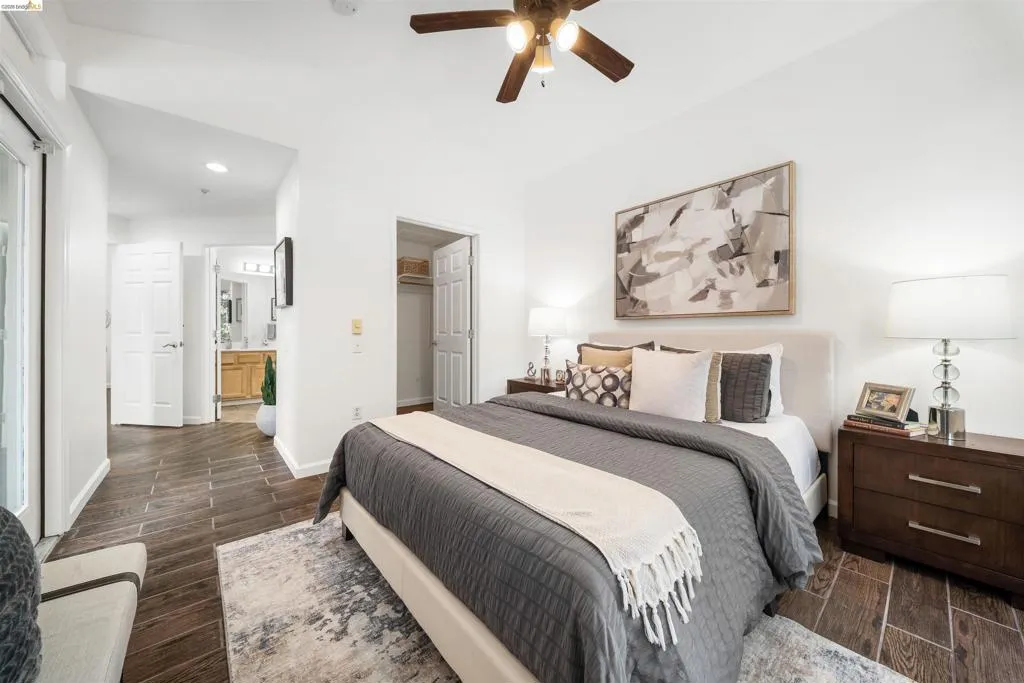 Bedroom with wood finish floors, a spacious closet, recessed lighting, connected bathroom, and a ceiling fan