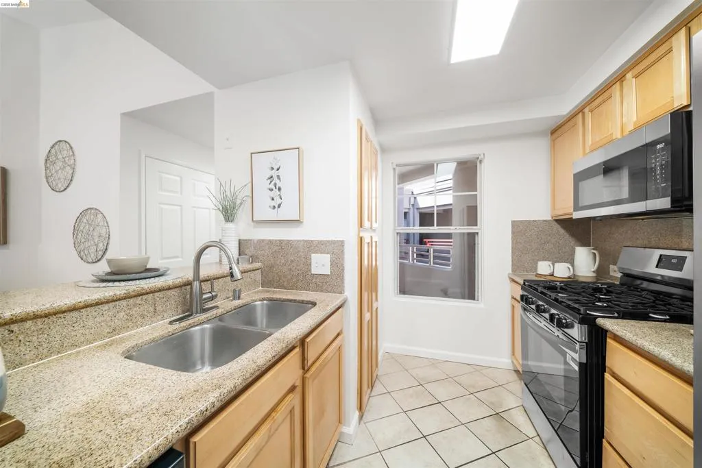 Kitchen featuring stainless steel appliances, light wood finish cabinets, and light stone counters