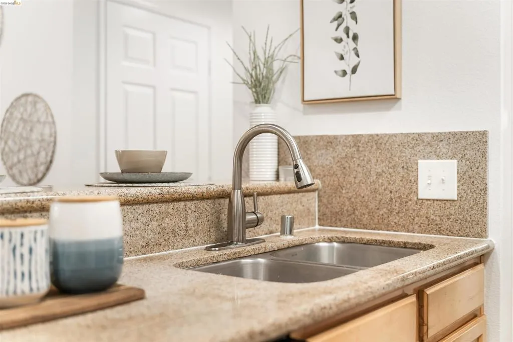 Kitchen view of light stone counters and decorative backsplash