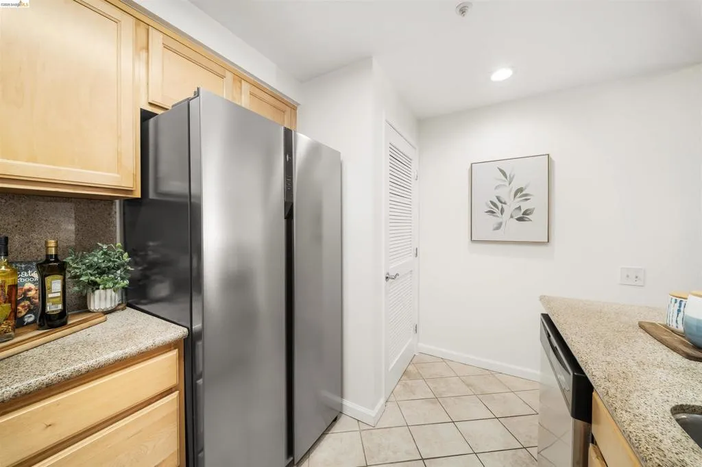 Kitchen featuring stainless steel appliances, light wood finish cabinets, light stone countertops, light tile patterned flooring, and recessed lighting