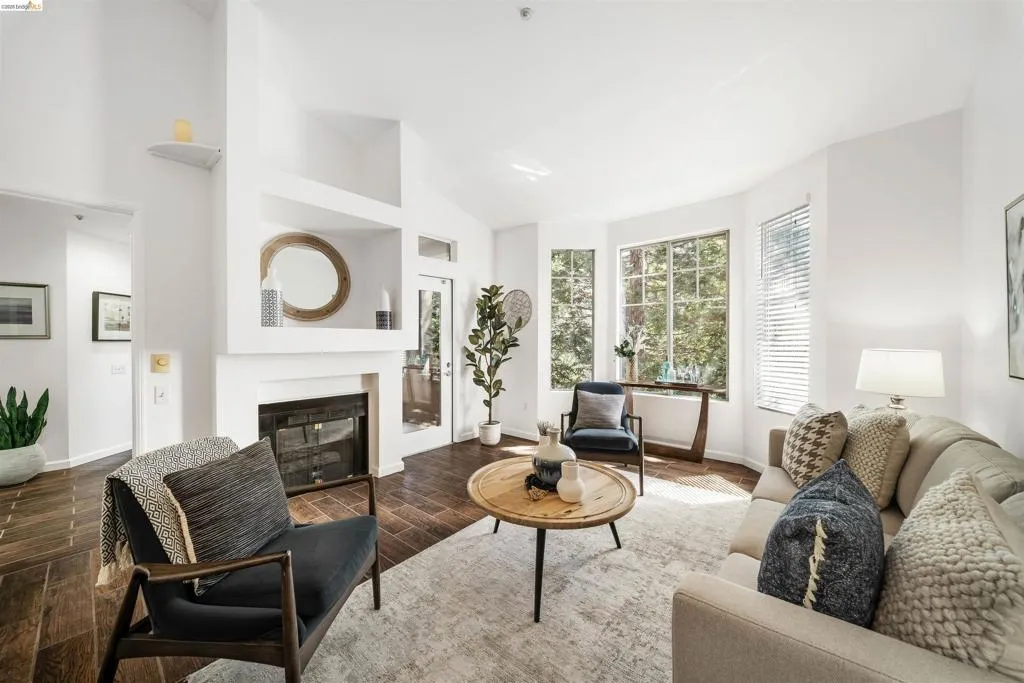 Living room featuring wood tiled floors, a glass covered fireplace, and lofted ceiling