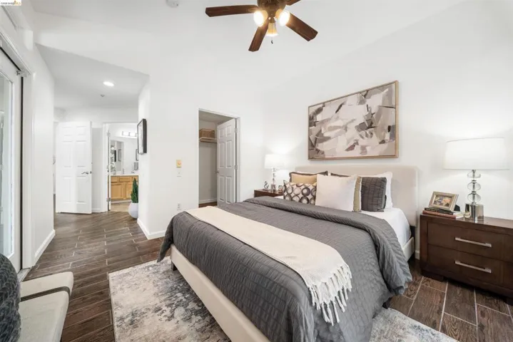 Bedroom with wood finish floors, a spacious closet, recessed lighting, connected bathroom, and a ceiling fan