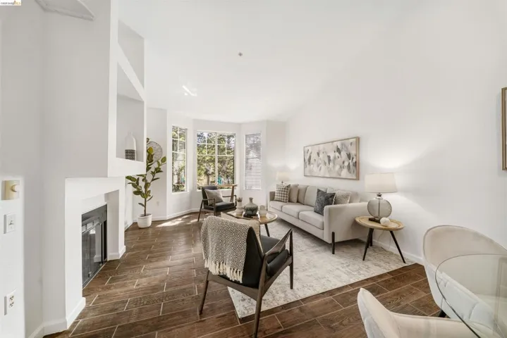 Living area with wood tiled floors, a glass covered fireplace, and lofted ceiling