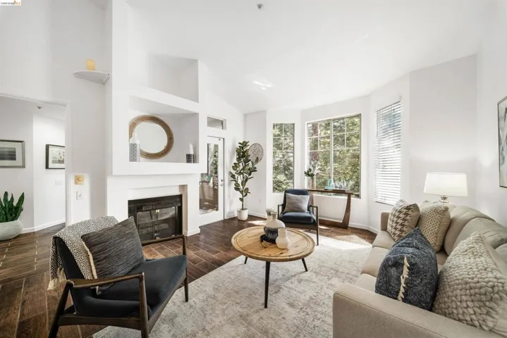 Living room featuring wood tiled floors, a glass covered fireplace, and lofted ceiling
