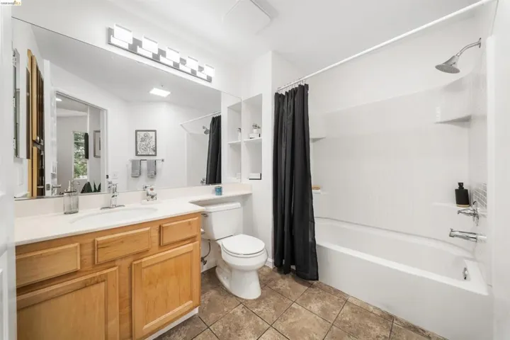 Full bathroom featuring vanity, shower / tub combo with curtain, and light tile patterned floors