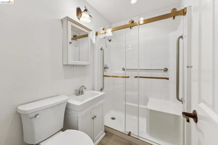 Full bathroom featuring a walk-in shower with gold-tone hardware, glass enclosure, and an integrated bench