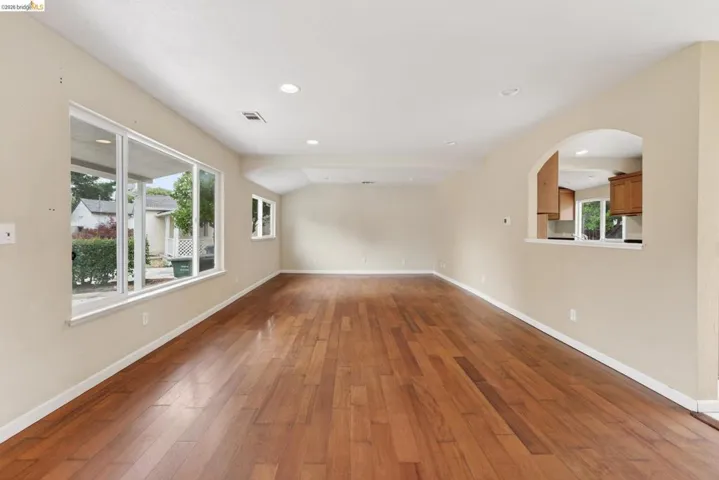 Expansive living area with wood-finish flooring, recessed lighting, and large windows
