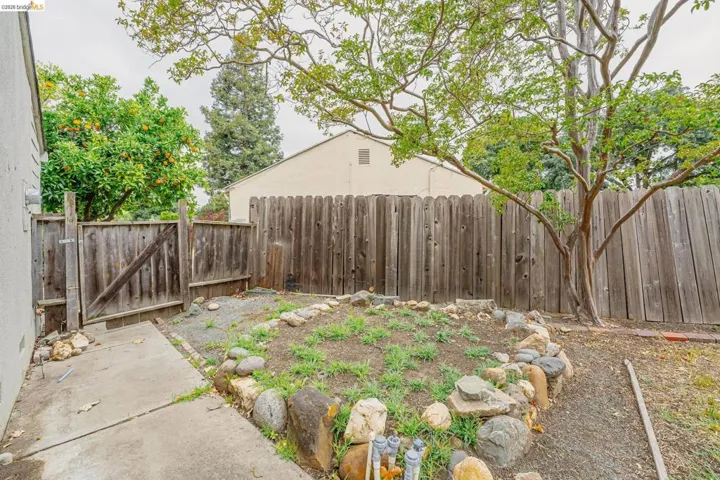 Enclosed backyard featuring a privacy fence, a concrete patio, and a rock-lined planting area
