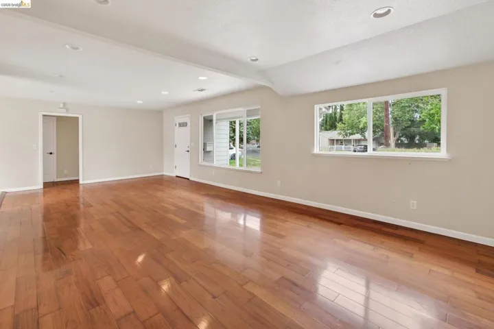 Spacious interior featuring wood-finish flooring, recessed lighting, neutral paint, a solid entry door, and multiple windows