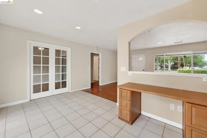 Light-toned square tile flooring extending throughout, complemented by white French doors with glass paneling