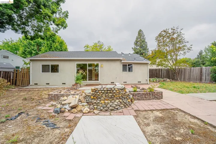 Rear exterior of the residence featuring a stucco finish and a dark shingle roof
