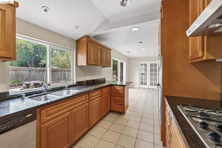 Kitchen featuring wood cabinetry, dark countertops, a double basin sink, and tile flooring