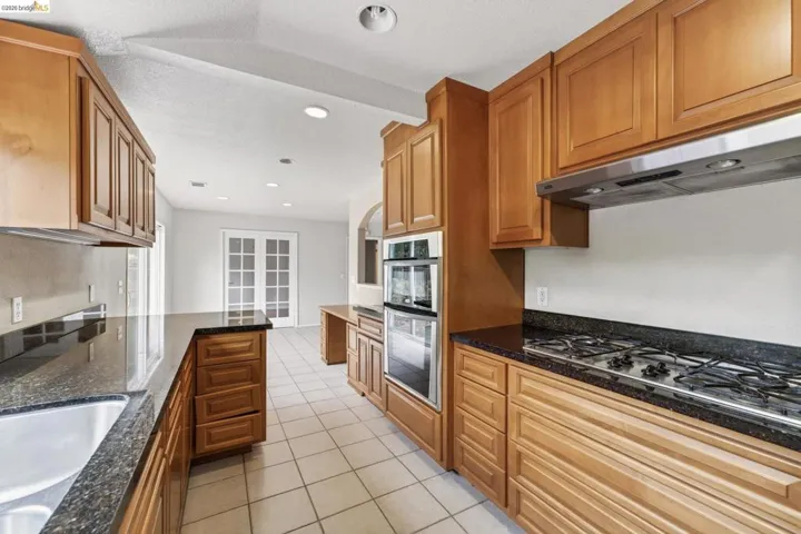 Kitchen featuring extensive wood cabinetry, dark speckled countertops, and tile flooring