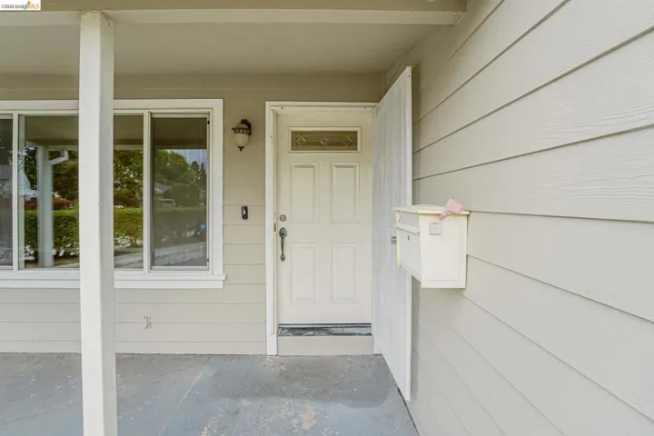 Entryway featuring a paneled door with decorative glass, an exterior wall light, and an adjacent window arrangement