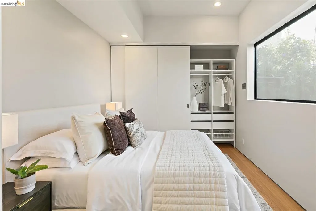 Bedroom featuring a built-in closet system with sliding doors, a large rectangular window, and recessed ceiling lighting