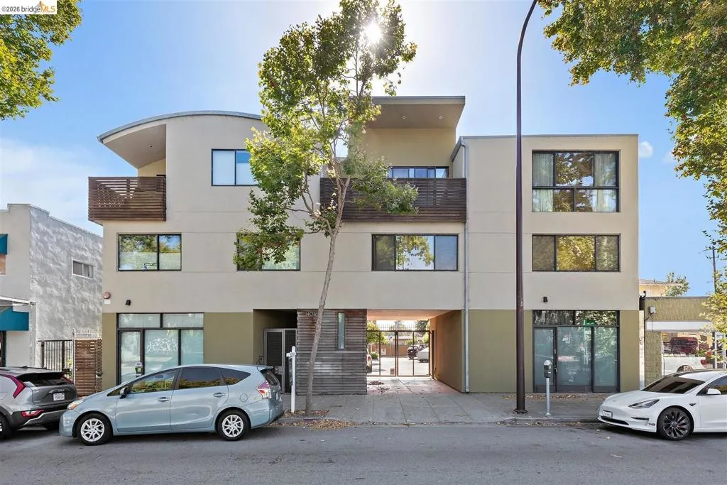 Modern multi-story building featuring a neutral stucco facade and dark-framed windows
