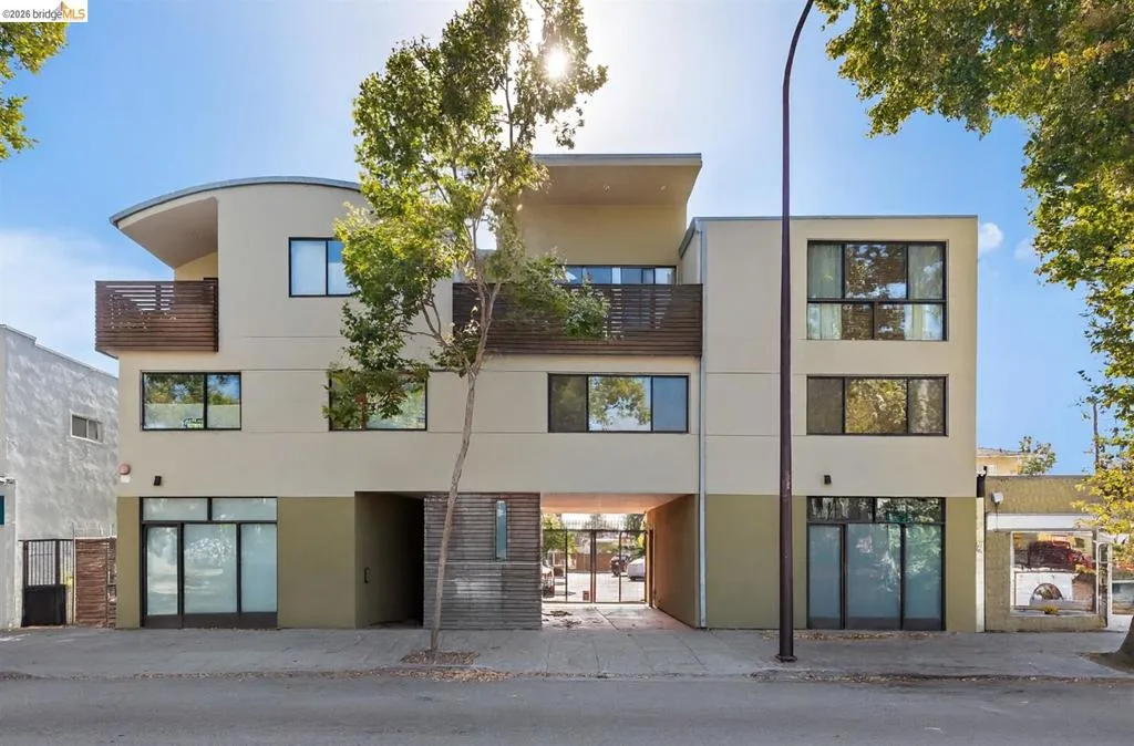 Contemporary multi-story building featuring a neutral-toned stucco facade with a curved roofline