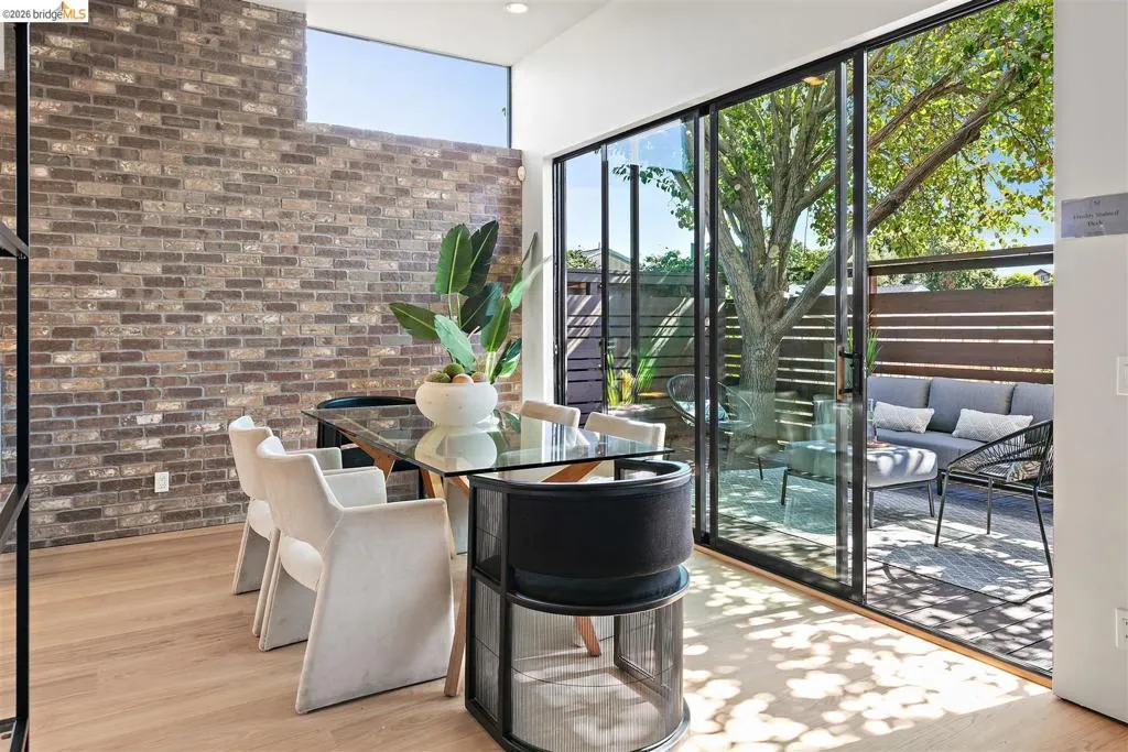 Spacious interior featuring a full-height brick accent wall, wood-finish flooring, and expansive sliding glass doors
