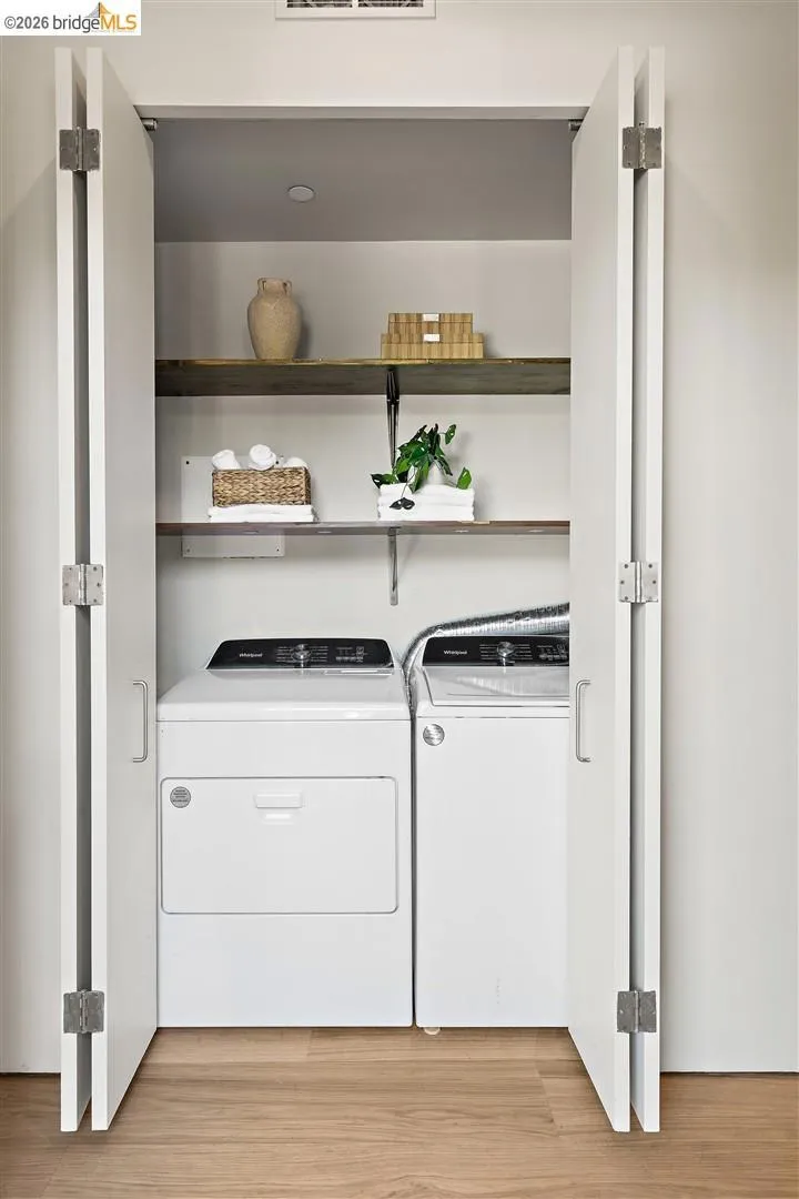 Dedicated laundry closet featuring bi-fold doors, wood-finish flooring, two upper shelves, and a recessed ceiling light