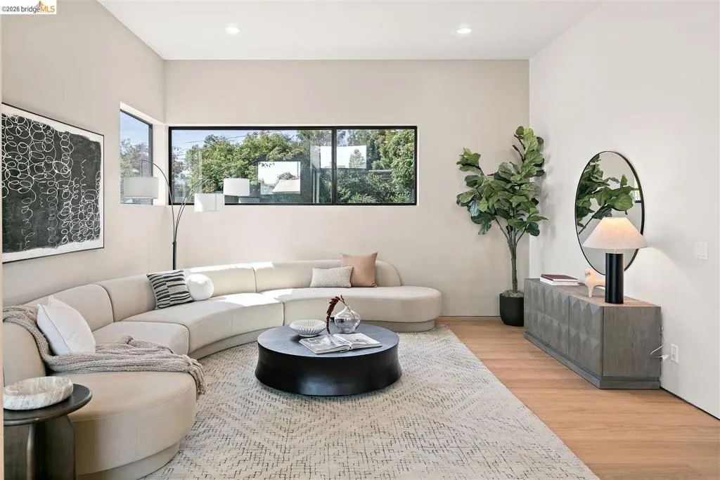 Spacious living area featuring high ceilings, light wood-finish flooring, and recessed lighting